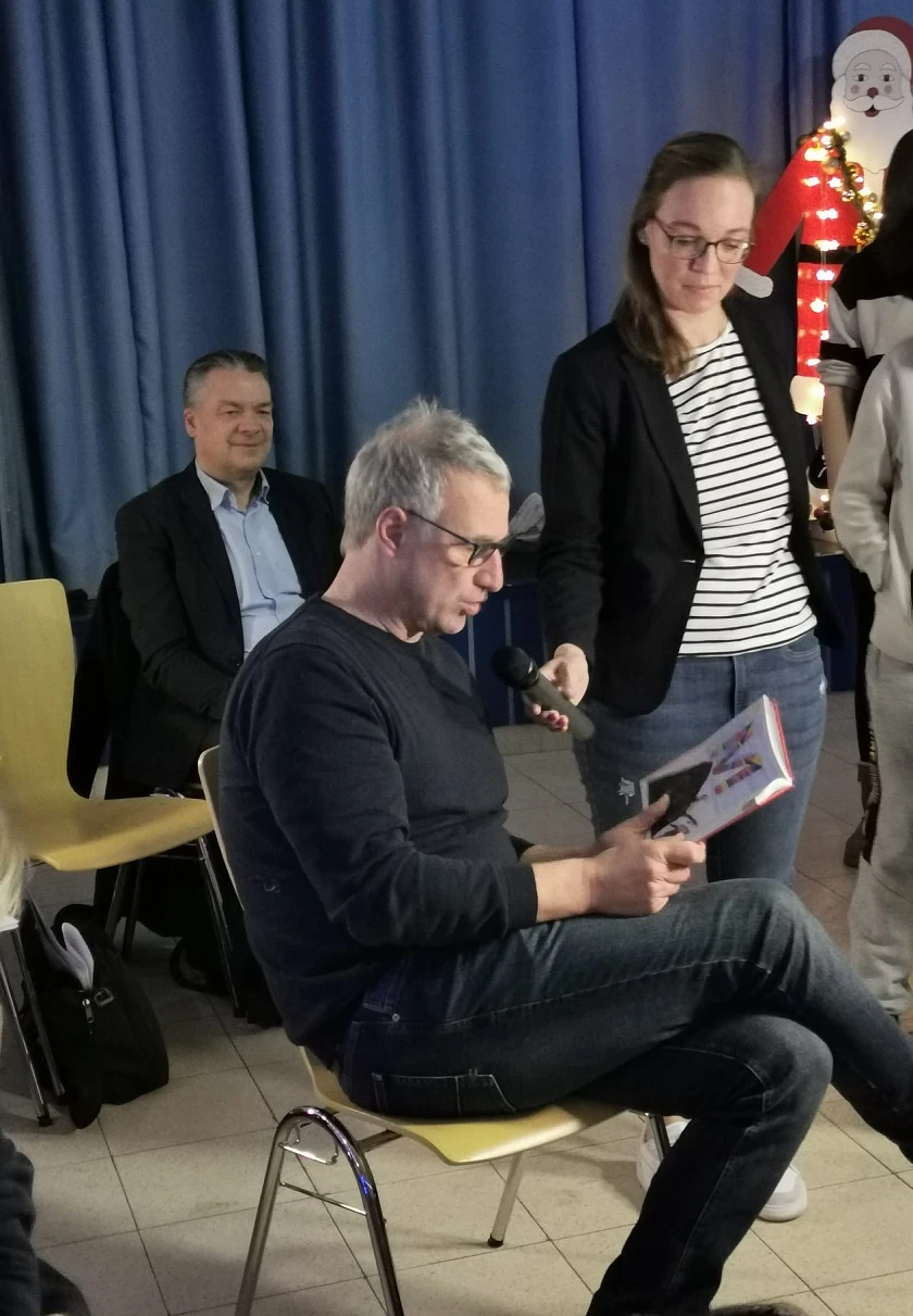 Marco Bode liest eine Geschichte vor. Frau Granig hält das Mikrofon