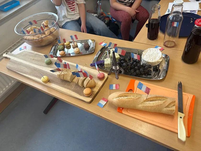 Baguette, Käse, Weintrauben angerichtet mit Frankreich Fahnen und gebasteltem Eifelturm